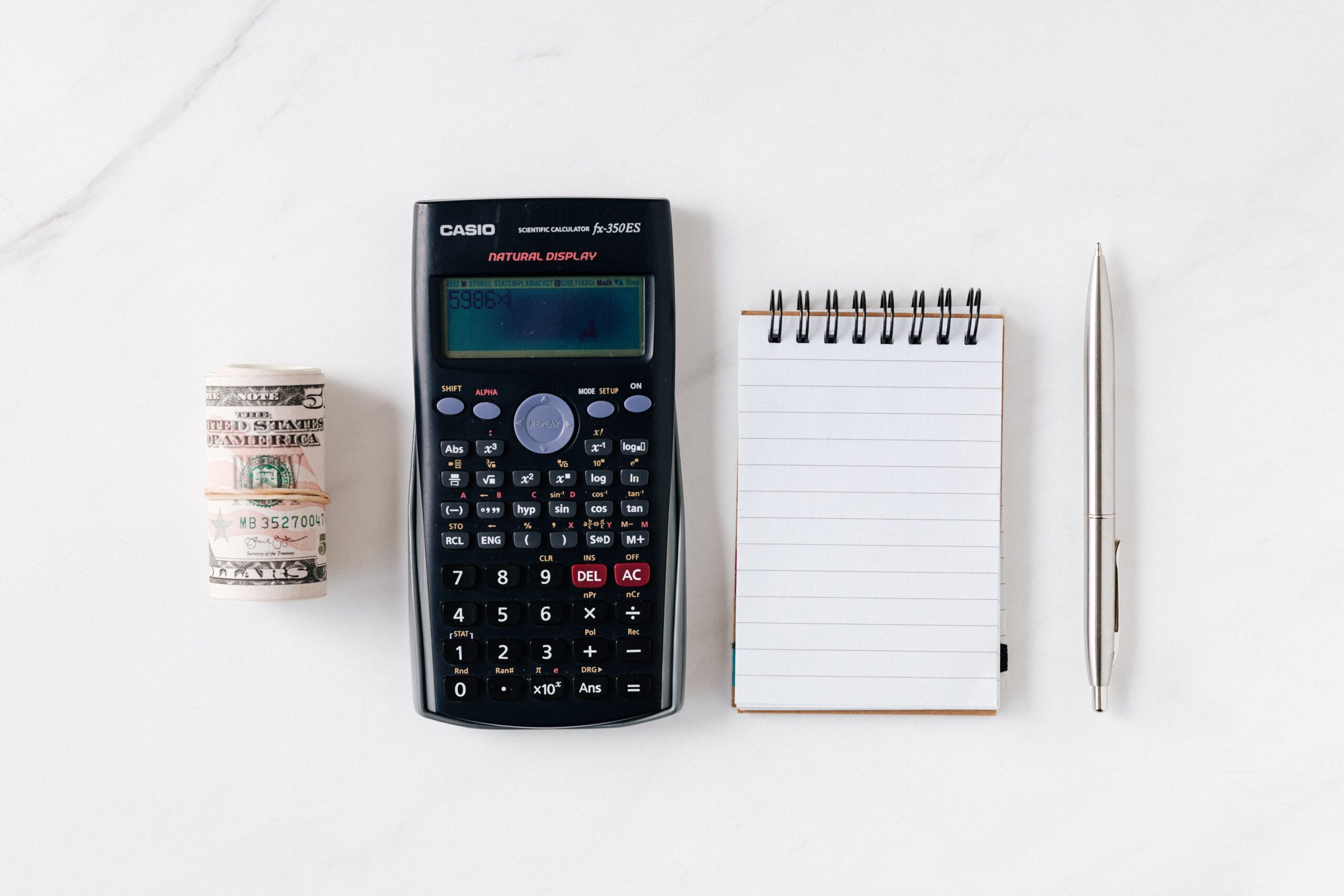 money, calculator, notebook and a pen on table - How much should I budget for food every month