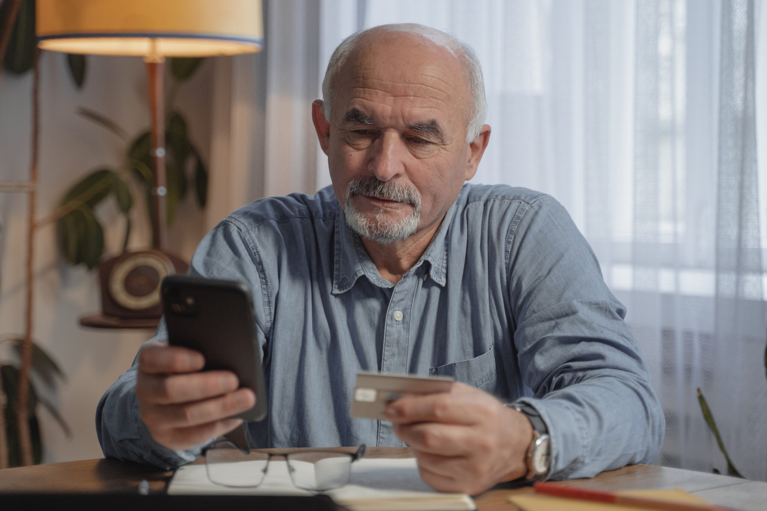 old man using a phone and credit card to shop online