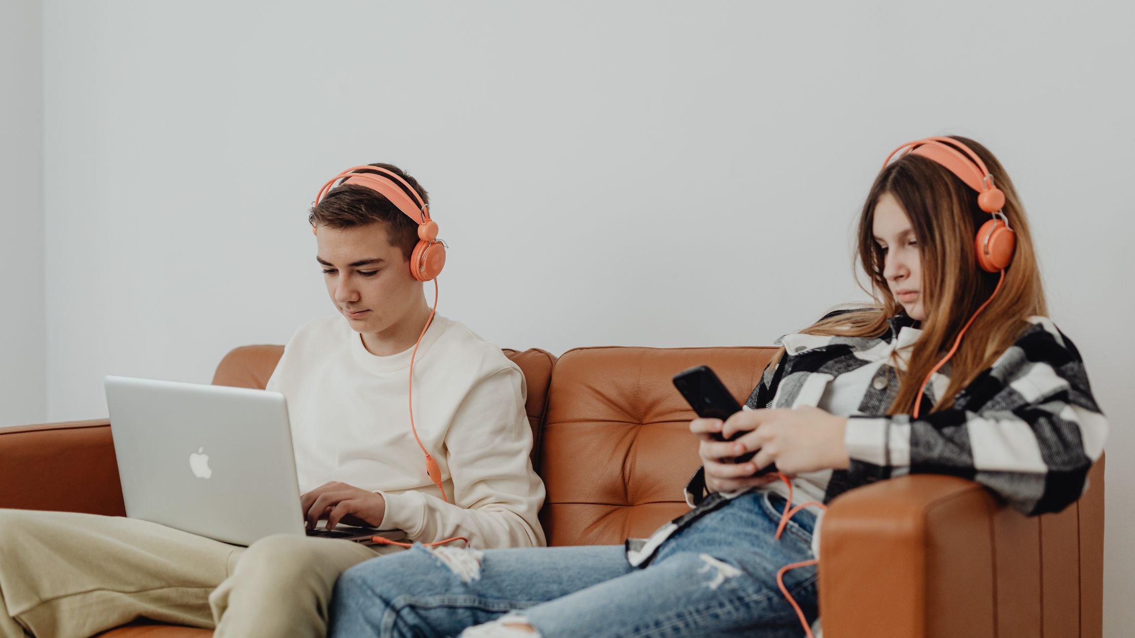 male teen on laptop and female teen on phone listening to music - make money as a teenager