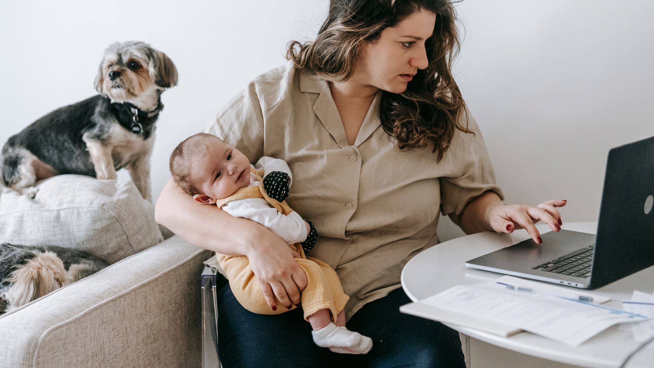 woman carrying her baby while working on her blog on a laptop