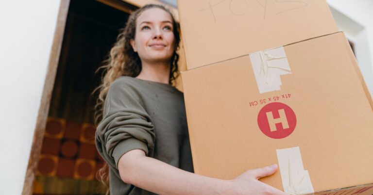 A lady carrying boxes from a van