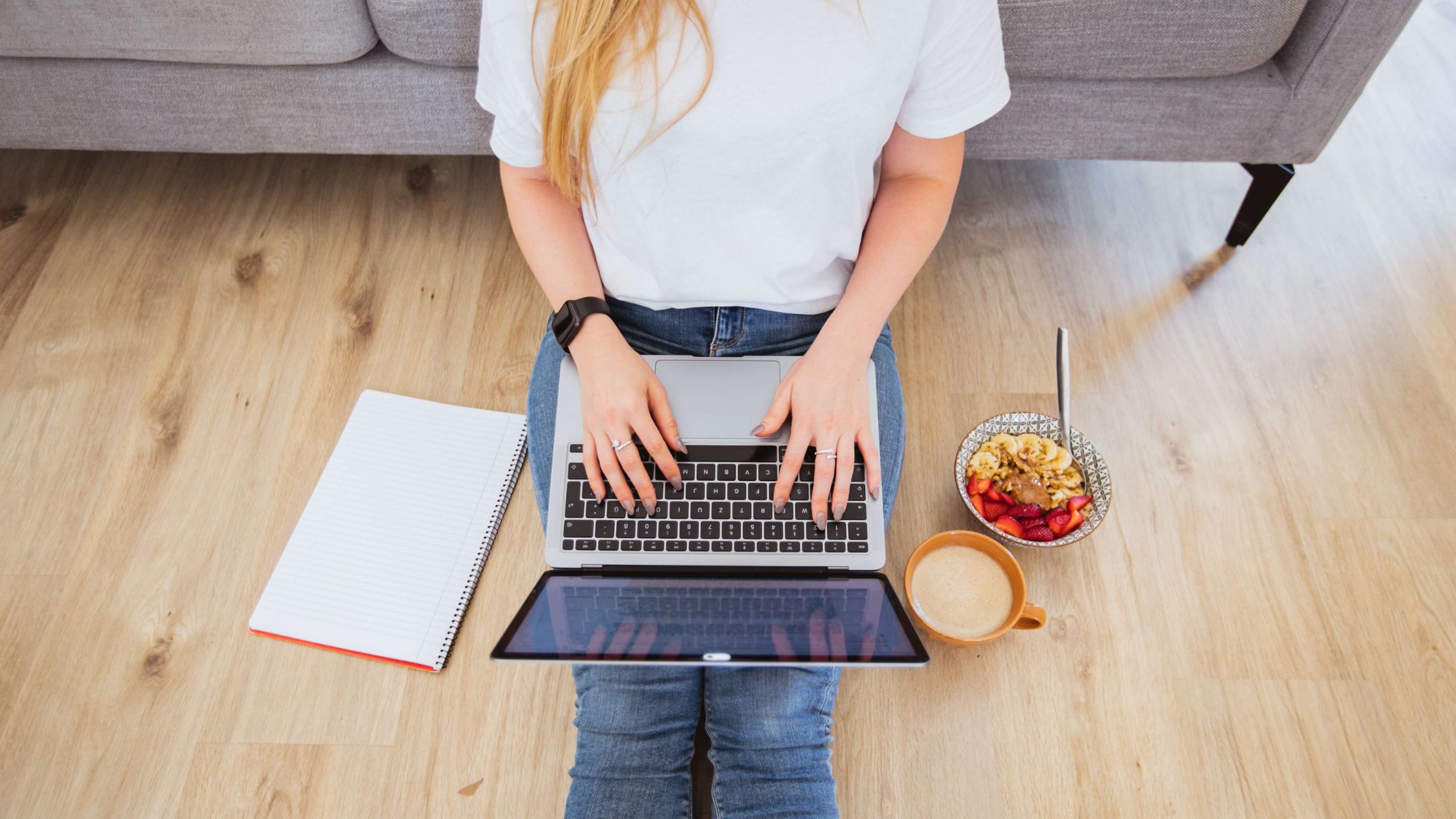 Lady sitting on the floor at home working on a laptop 